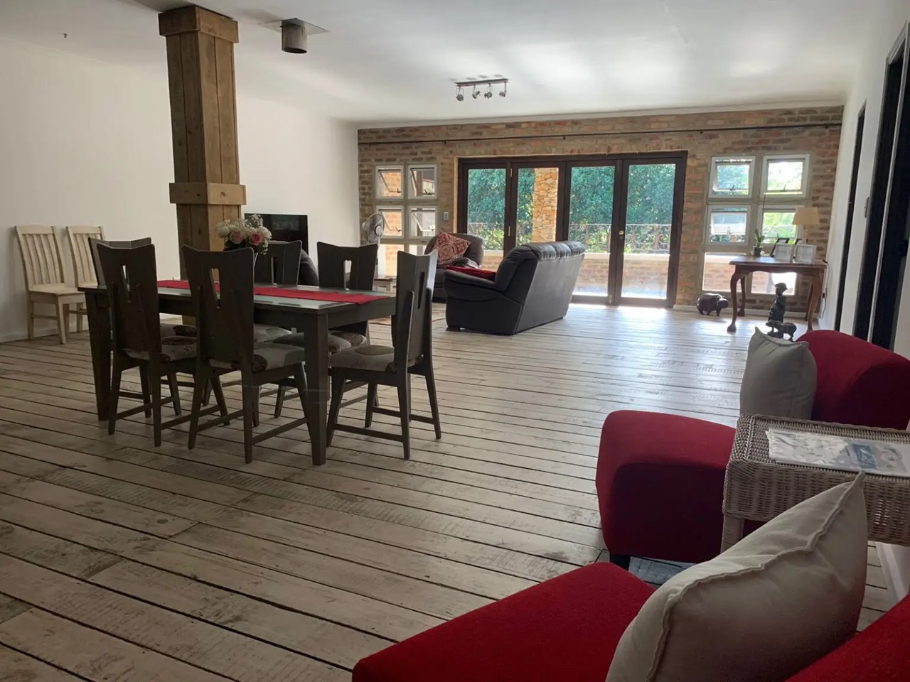 Open-plan living room with brick fireplace wall and doors to the garden